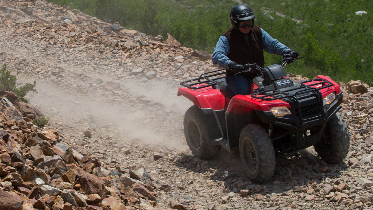 A rider hauling some hay on the back of a Honda Rancher