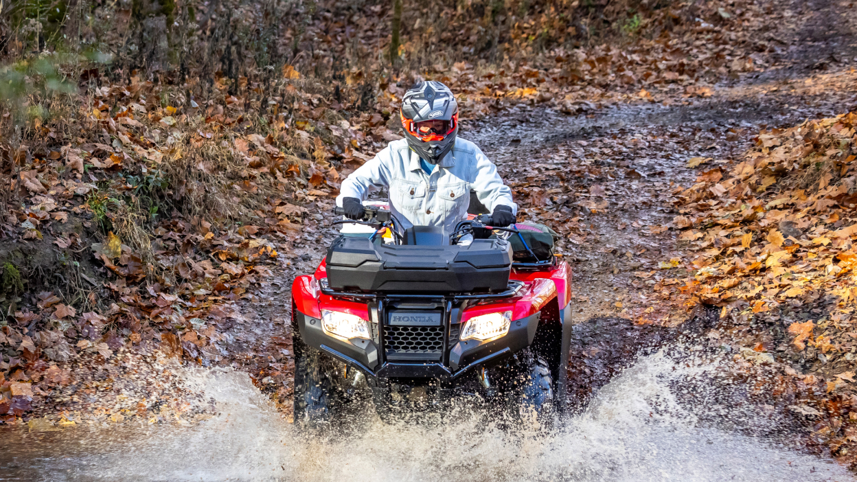 Driver going through muddy water. Front facing, Avenger Red. Dirt road and woodland background.