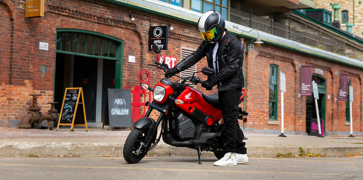 Un cavalier qui monte sur une Honda Navi à l'extérieur d'une galerie d'art