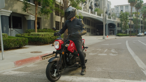 Un cavalier en noir à cheval sur une Honda Navi sur une route