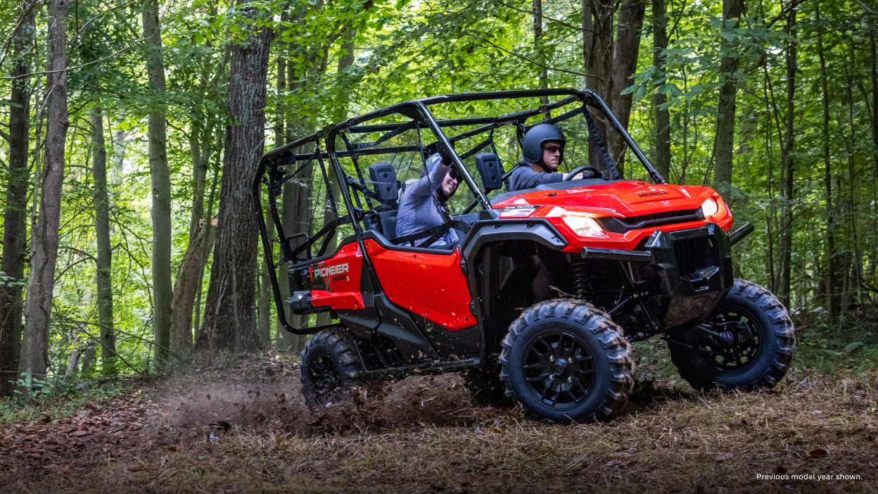 Riders in a Pioneer 1000 on a forest trail